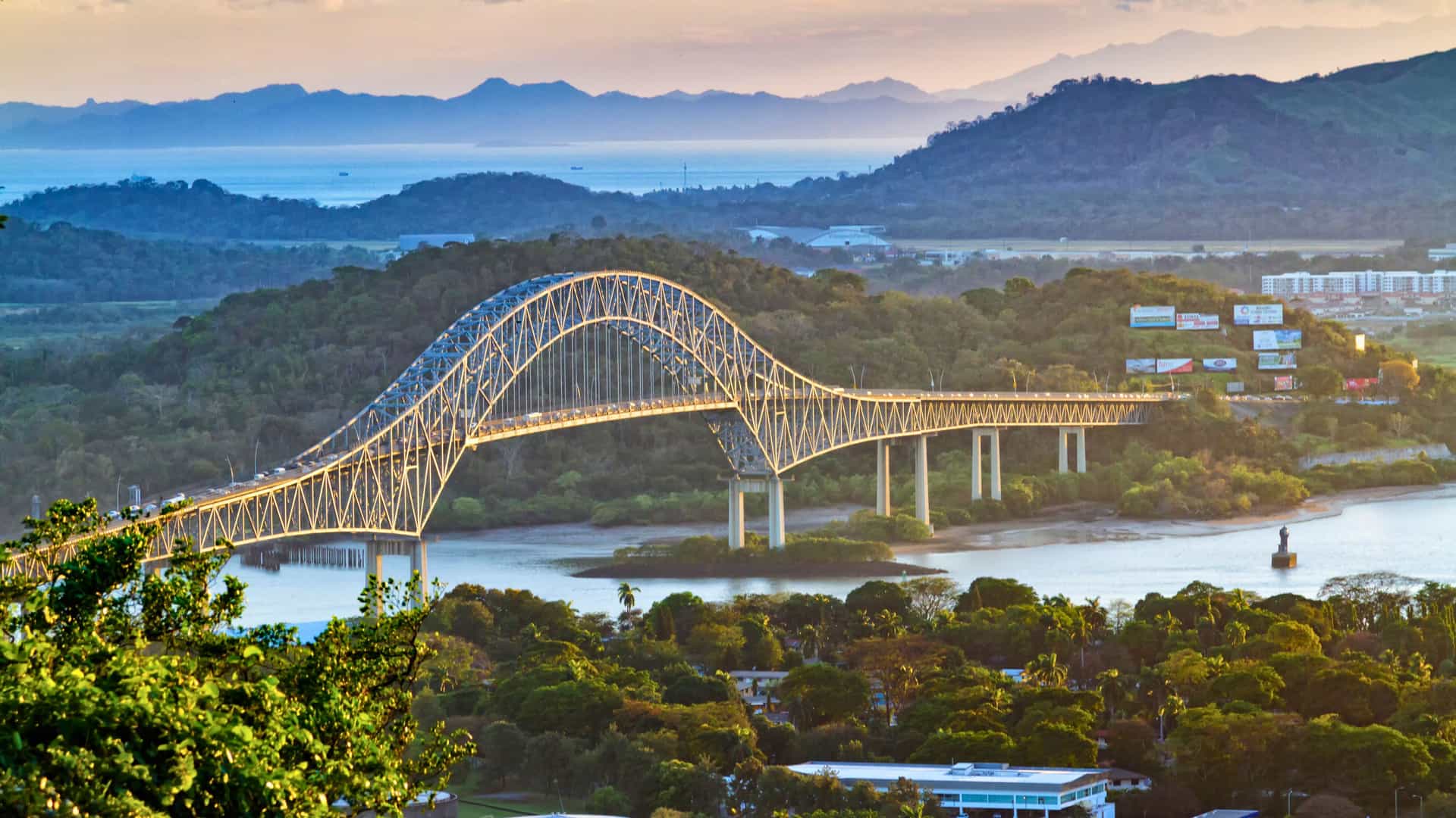 Explora journey view of the scenic bridge crossing the Panama Canal surrounded by lush greenery and mountains.