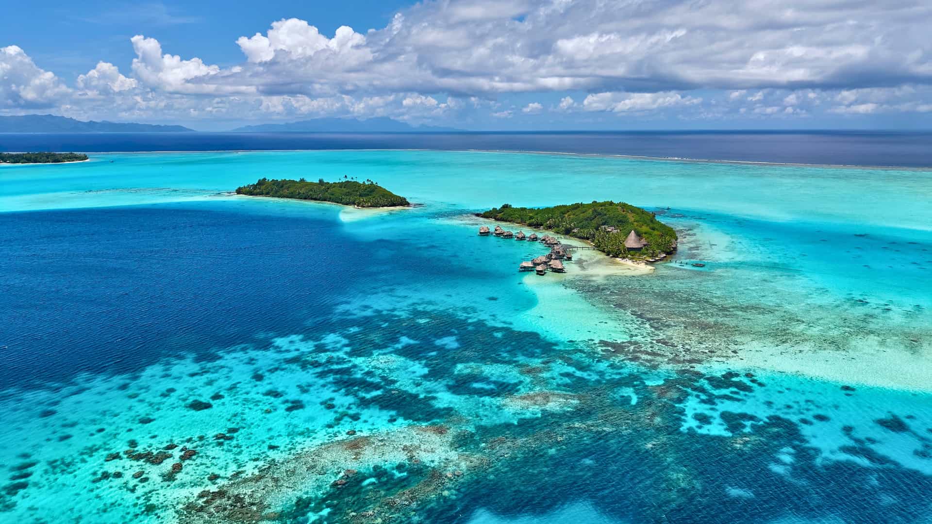 Explora journey aerial view of tropical islands, coral reefs, and turquoise lagoon waters in South Pacific Tahiti.