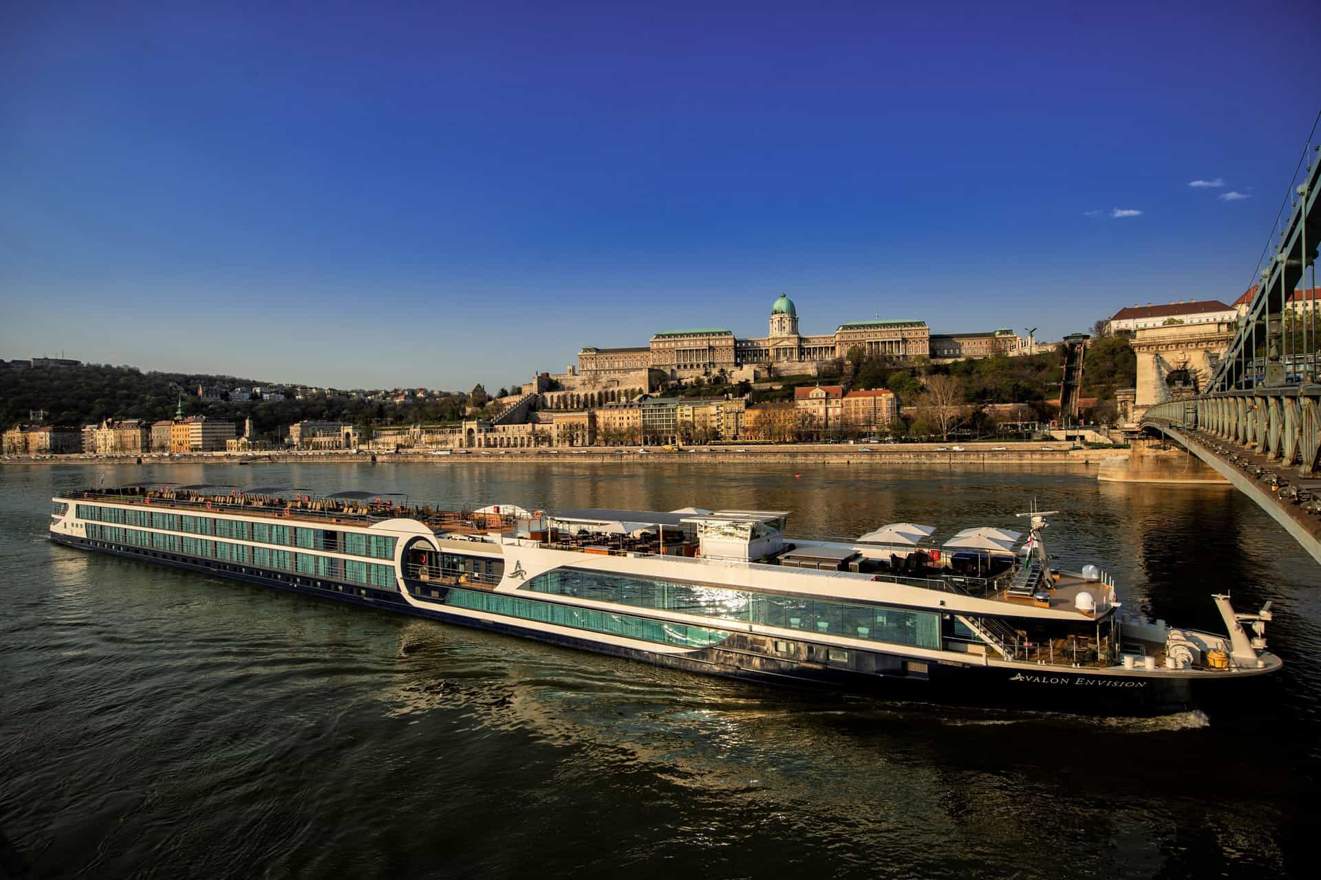 Exterior shot showcasing the modern design of the Avalon Envision river ship sailing and approaching a bridge.