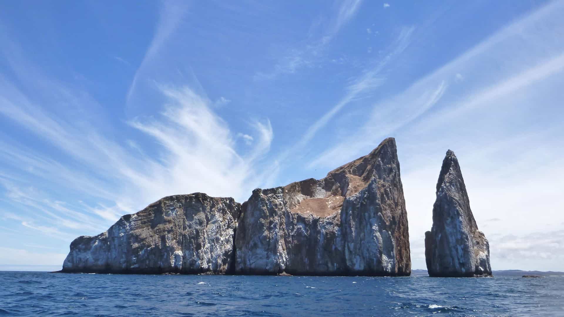 Kicker Rock (Leon Dormido) formation in Galapagos near San Cristobal Island under blue sky.