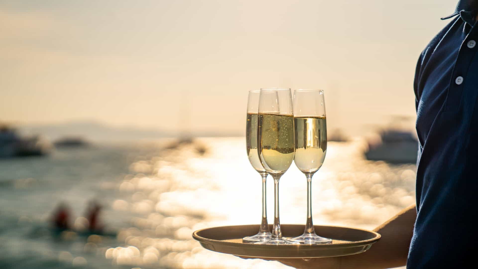 Luxury cruise waiter serving champagne.