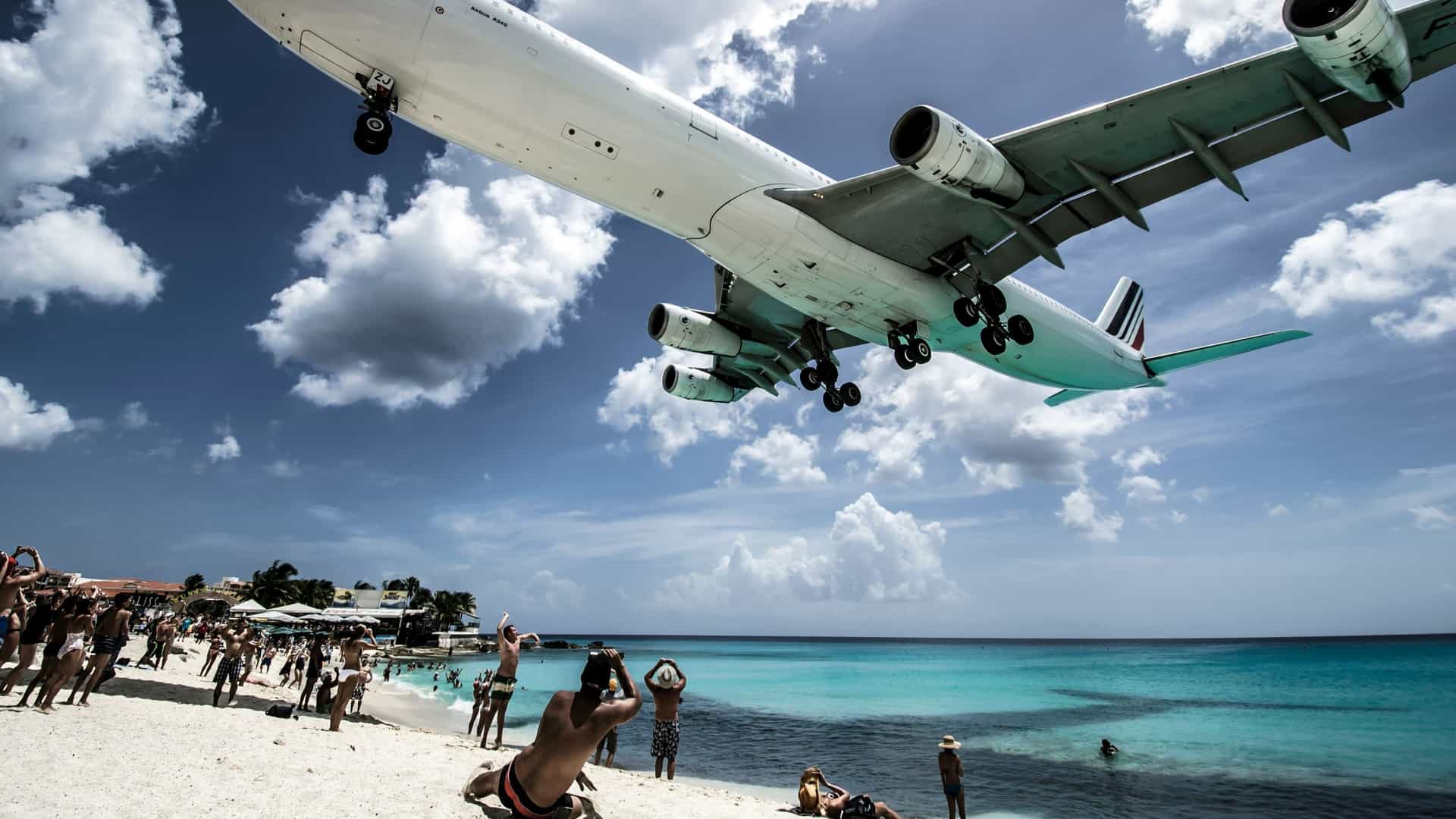 A crowd of people by the shore taking photos of the famous airplane spotting at Maho Beach,  St. Martin Island.