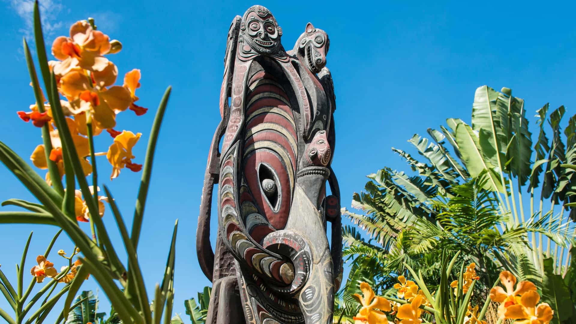 A traditional mask surrounded by yellow and orange flowers in Papua New Guinea.