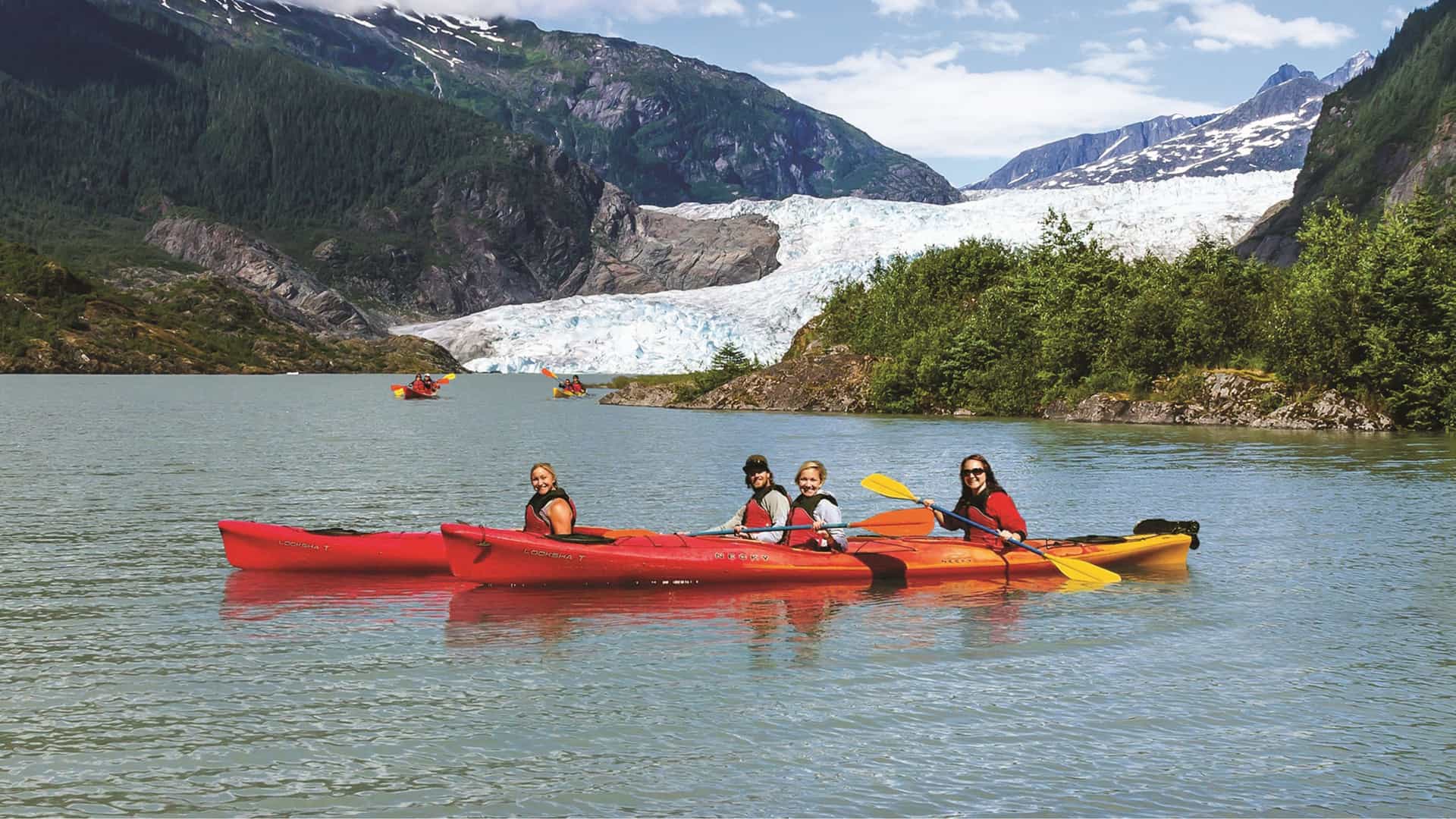 Kayakers pose for a group photo in front of the Mendenhall Glacier in Juneau, Alaska.