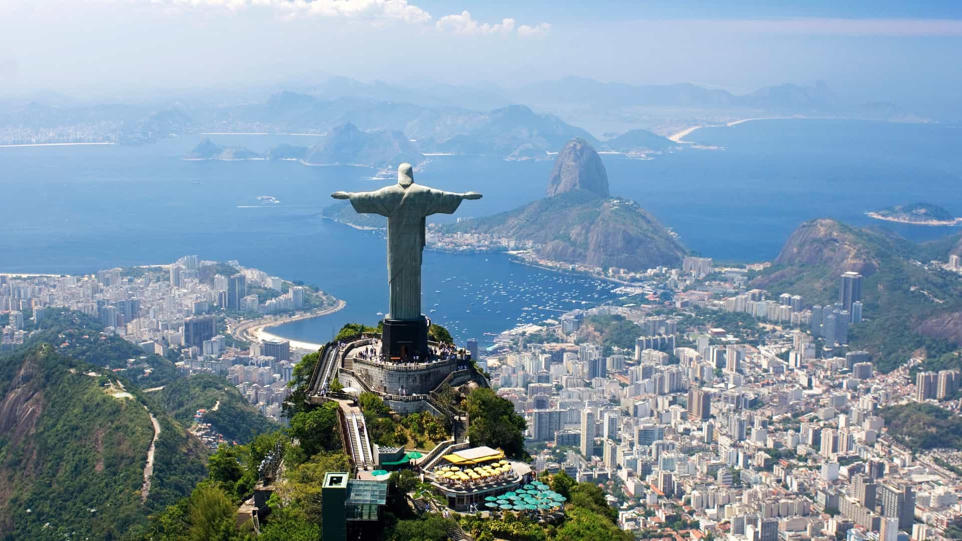 Aerial view of Christ the Redeemer statue overlooking Rio de Janeiro, South America, with Sugarloaf Mountain and Guanabara Bay in the background.