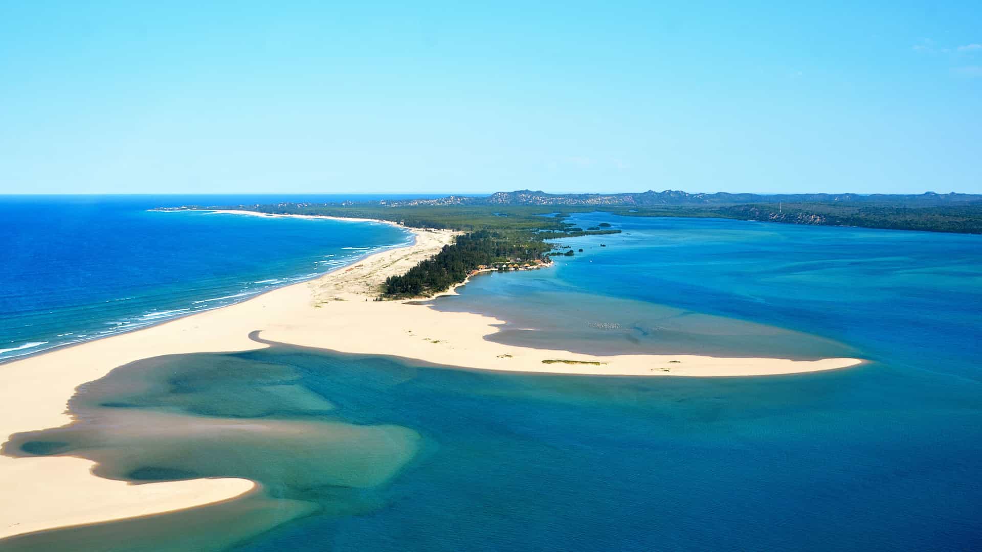 Aerial view of Pomene beach in Mozambique, Northern Africa, showing sandy shores, clear blue waters, and lush coastal greenery.