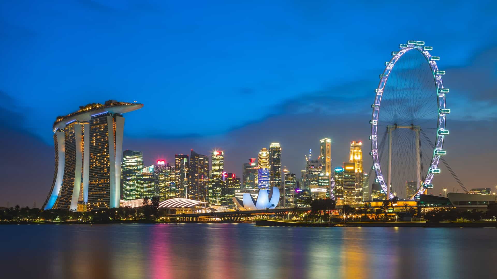 Vibrant Singapore city skyline at night, including Marina Bay Sands and the Singapore Flyer, a popular port of call in Southeast Asia on Norwegian Cruise Line Asia cruises.