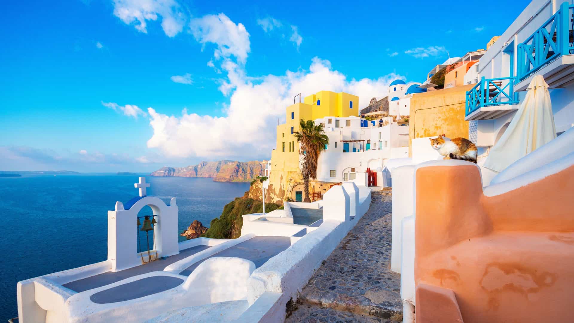 The iconic whitewashed buildings with blue domes and bright yellow facades in Santorini, Greece, with a view of the Aegean Sea, a popular Mediterranean.