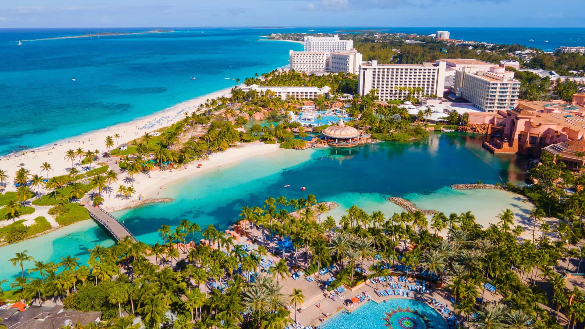 An aerial view of a luxurious resort with white sand beaches, turquoise waters, and palm trees in Nassau, Bahamas, a popular destination for Oceania cruises.