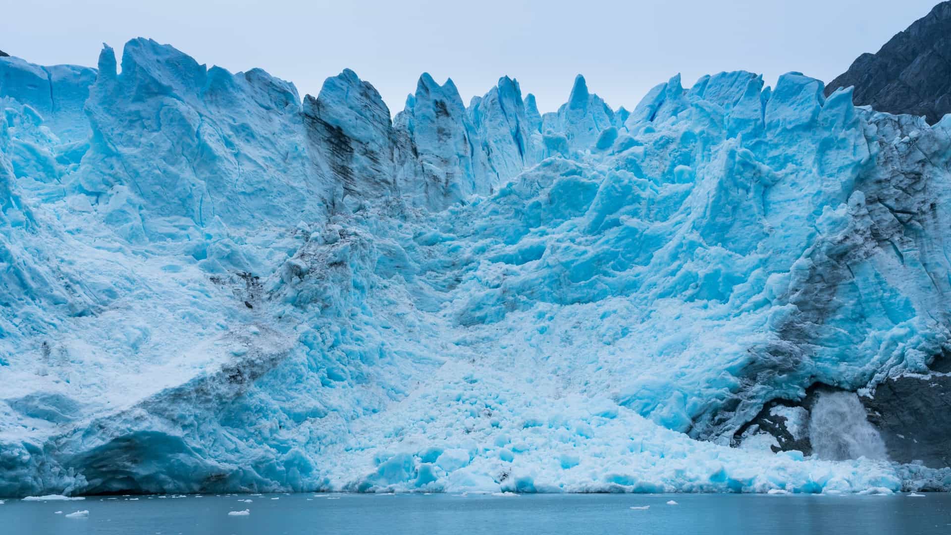 Águila Glacier, Chile, a stunning, large glacier with deep blue ice and crevasses, set against a rocky mountain backdrop.