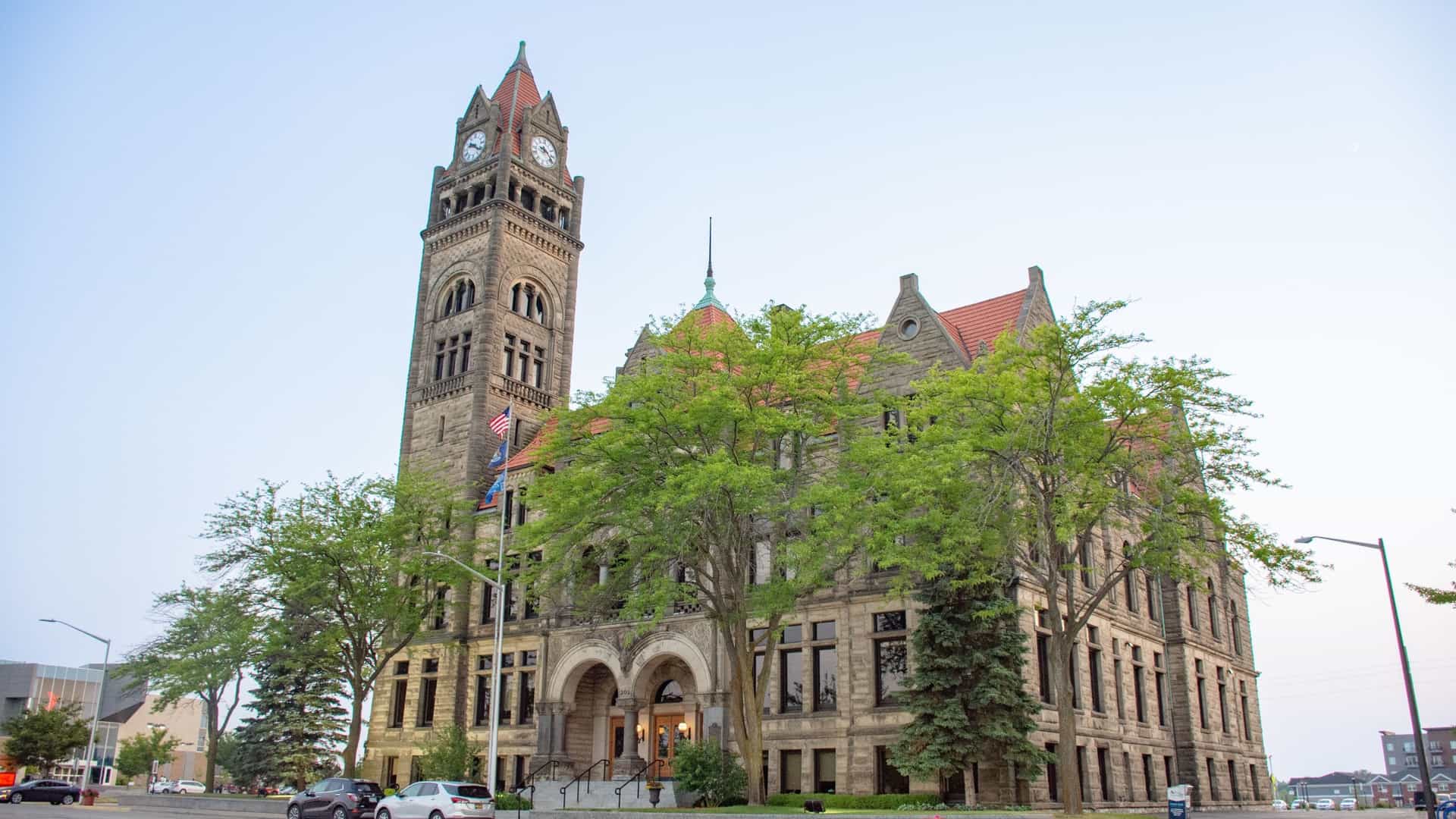 A grand, historic stone building, the Bay County Courthouse, stands tall with a clock tower in Bay City, Michigan.