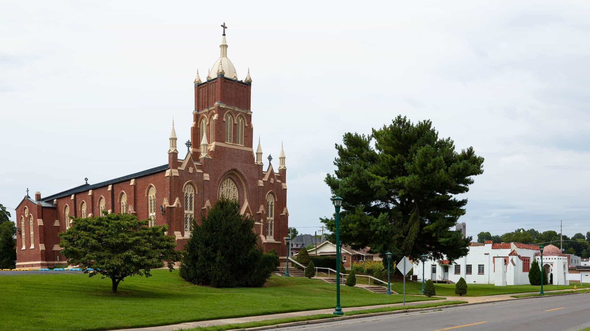 A beautiful side view of the historic St. Vincent de Paul Church in Cape Girardeau, Missouri, featuring its striking red brick architecture and tall bell tower.