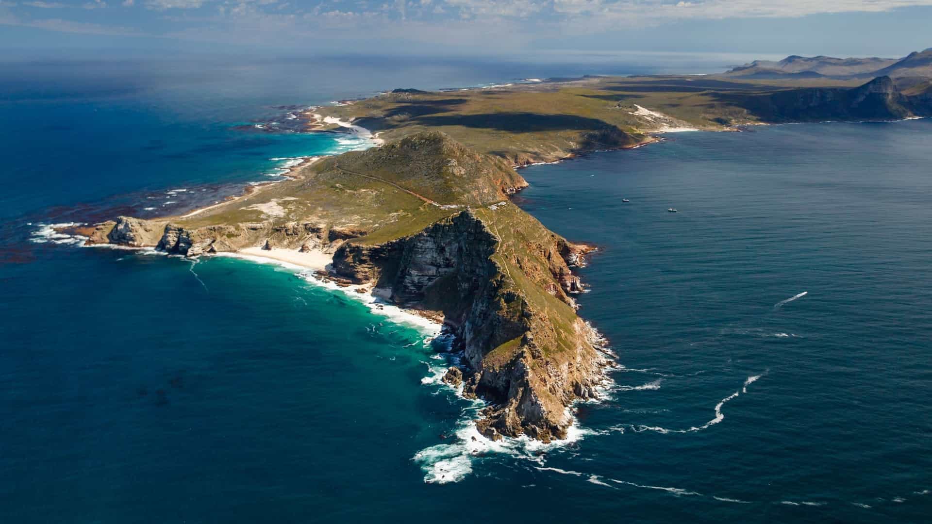 An aerial view of the rugged coastline of the Cape of Good Hope, South Africa, showcasing dramatic cliffs, pristine beaches, and the deep blue ocean.
