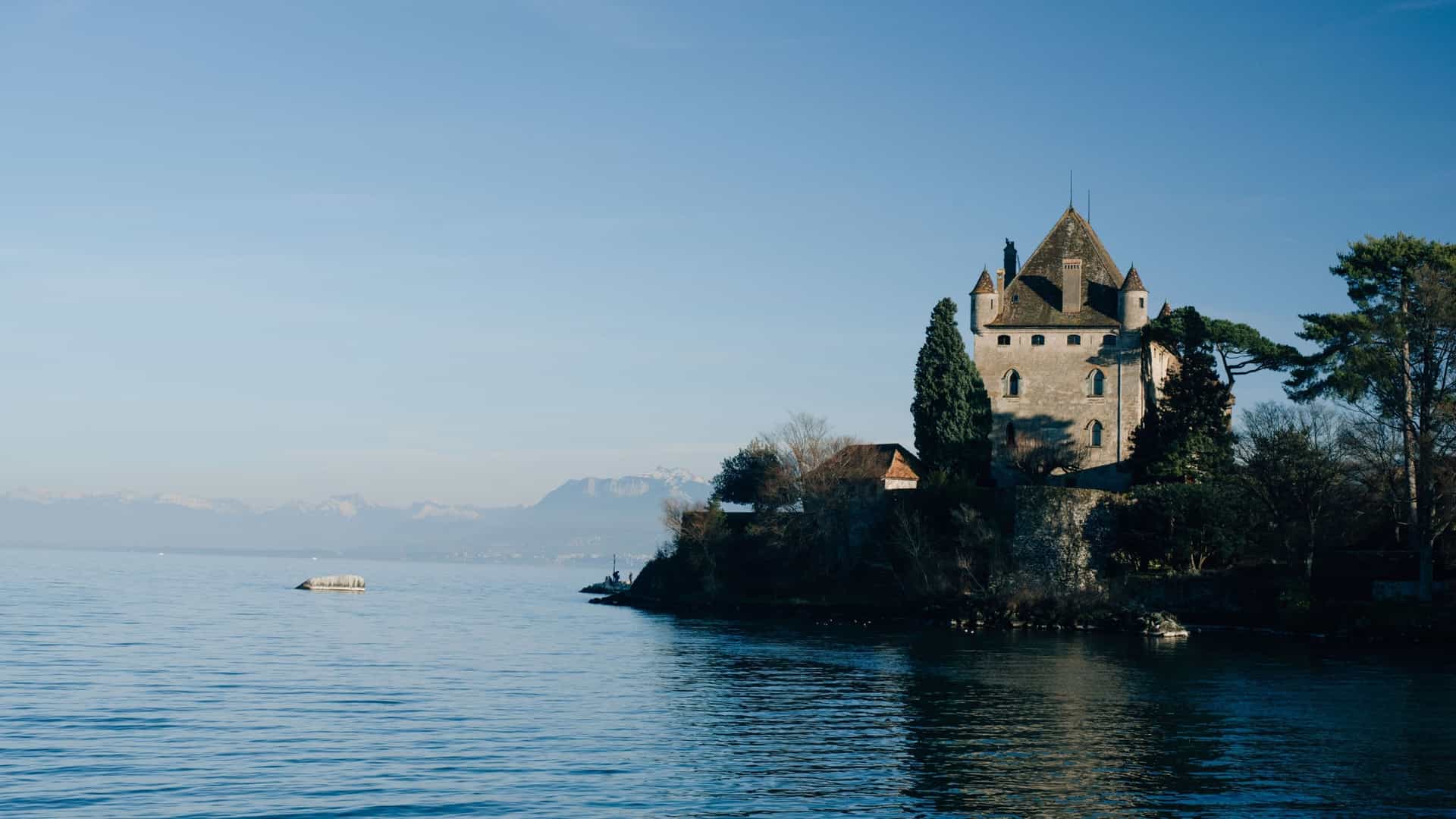 A picturesque view of the Château de Chillon, a historic medieval castle situated on a rocky islet on the banks of Lake Geneva in Switzerland.