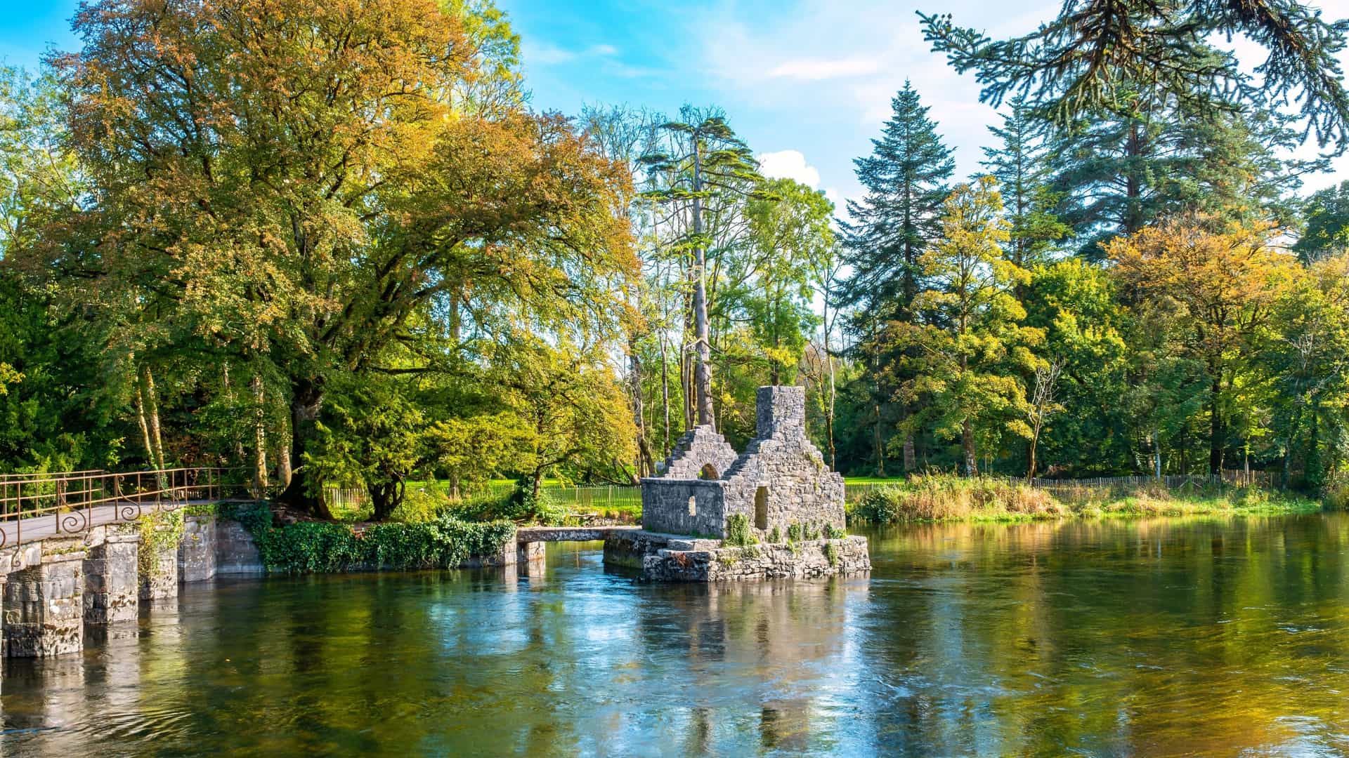 Ruins of a stone fishing house on an island in the River Cong, surrounded by autumn trees in County Mayo, Ireland.
