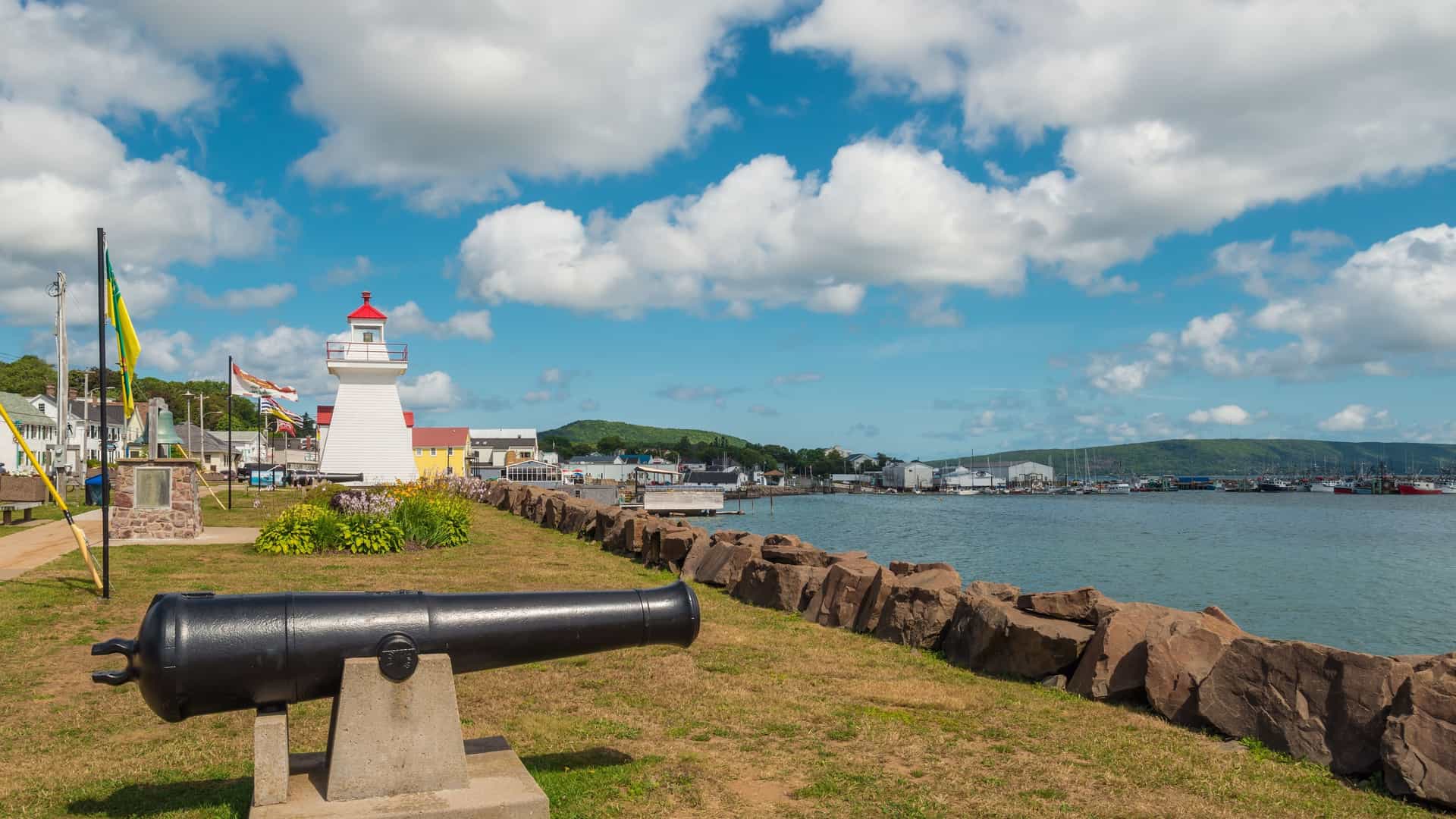 Digby waterfront in Nova Scotia, Canada, with a cannon in the foreground and the white Digby Lighthouse near the harbor.