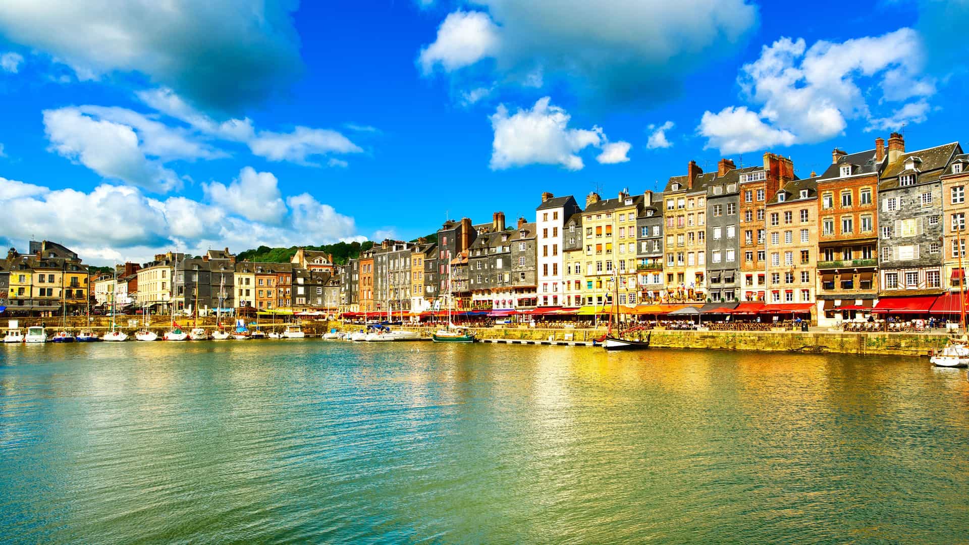 A beautiful scenic shot of the colorful, old-world houses and buildings lining the waterfront of the historic port of Honfleur, France.
