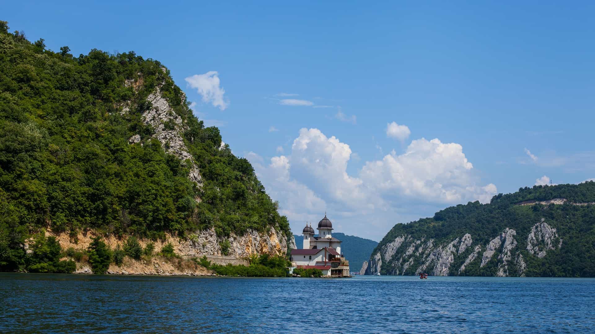 A beautiful orthodox monastery, Mănăstirea Mraconia, sits at the base of a forested cliff along the Danube River near the Iron Gates Gorge.
