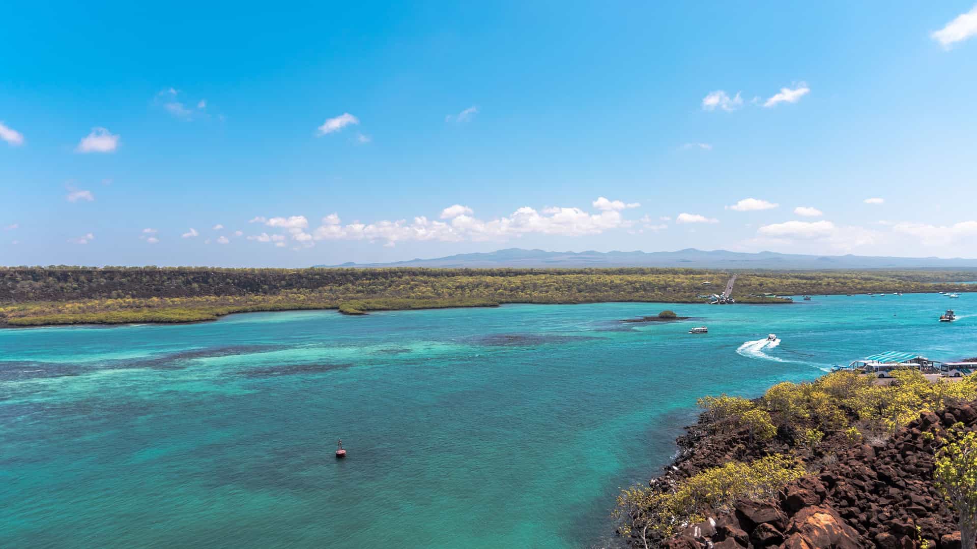 A panoramic view of the turquoise waters of the Itabaca Channel and the ferry dock, surrounded by lush green islands under a bright blue sky.