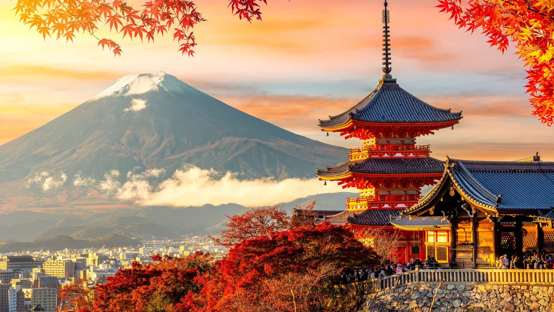 "A scenic view of the iconic Mount Fuji with a snow-capped peak, framed by colorful autumn leaves, and the vibrant red Kiyomizu-dera Temple pagoda in the foreground in Kyoto, Japan.  "