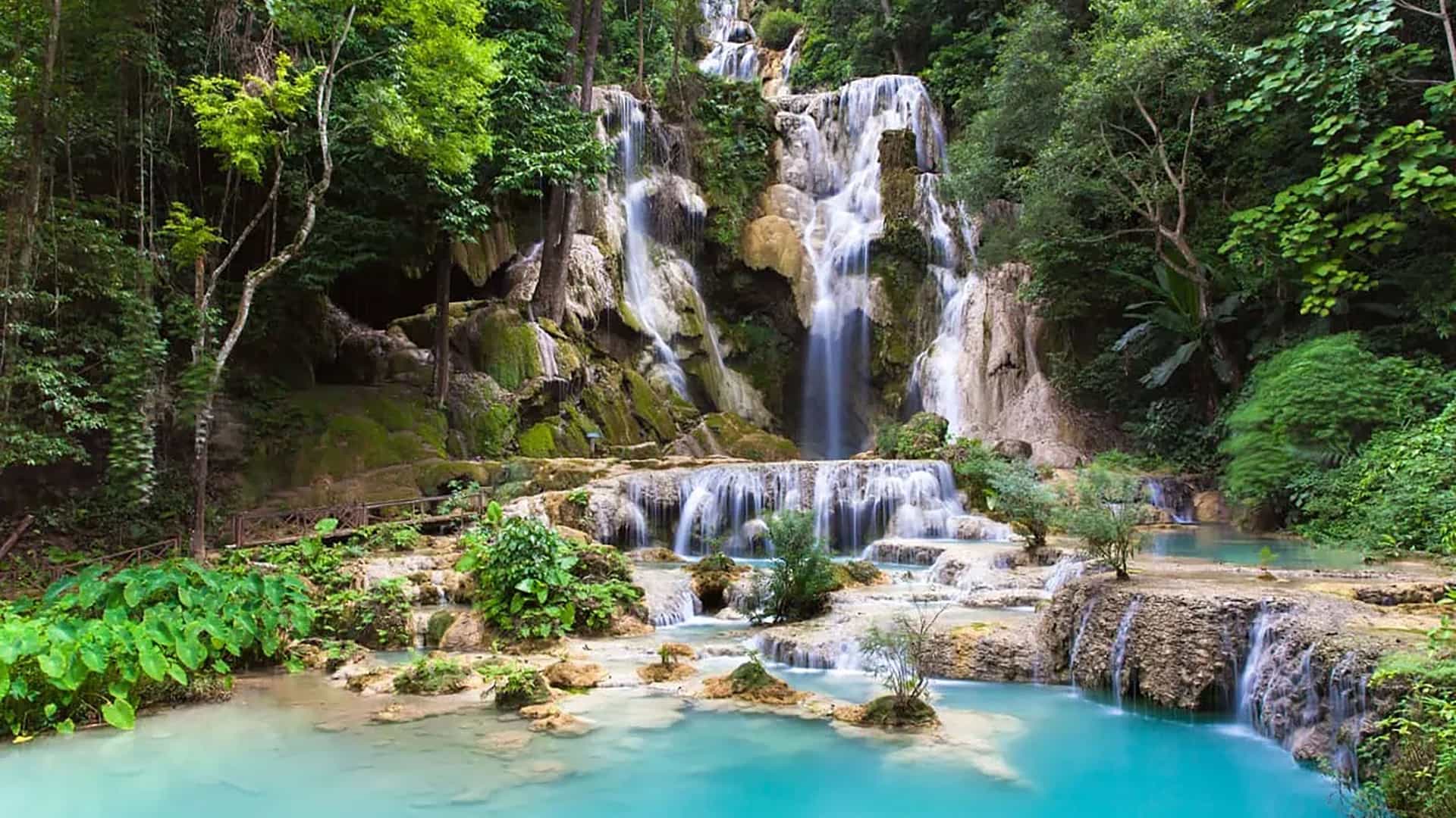 "A beautiful long-exposure shot of the multi-tiered Kuang Si Falls in Luang Prabang, Laos, with its stunning turquoise pools and lush green forest surroundings.  "
