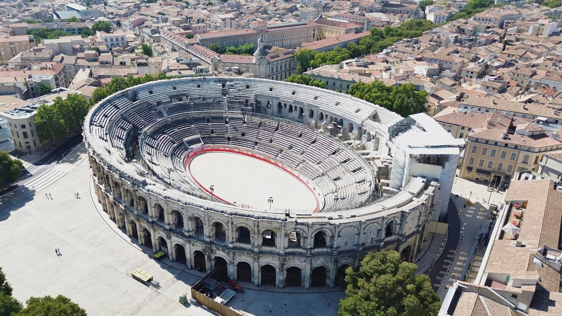 An aerial view of the remarkably well-preserved Roman amphitheater, the Arènes de Nîmes, surrounded by the modern city of Nîmes, France.