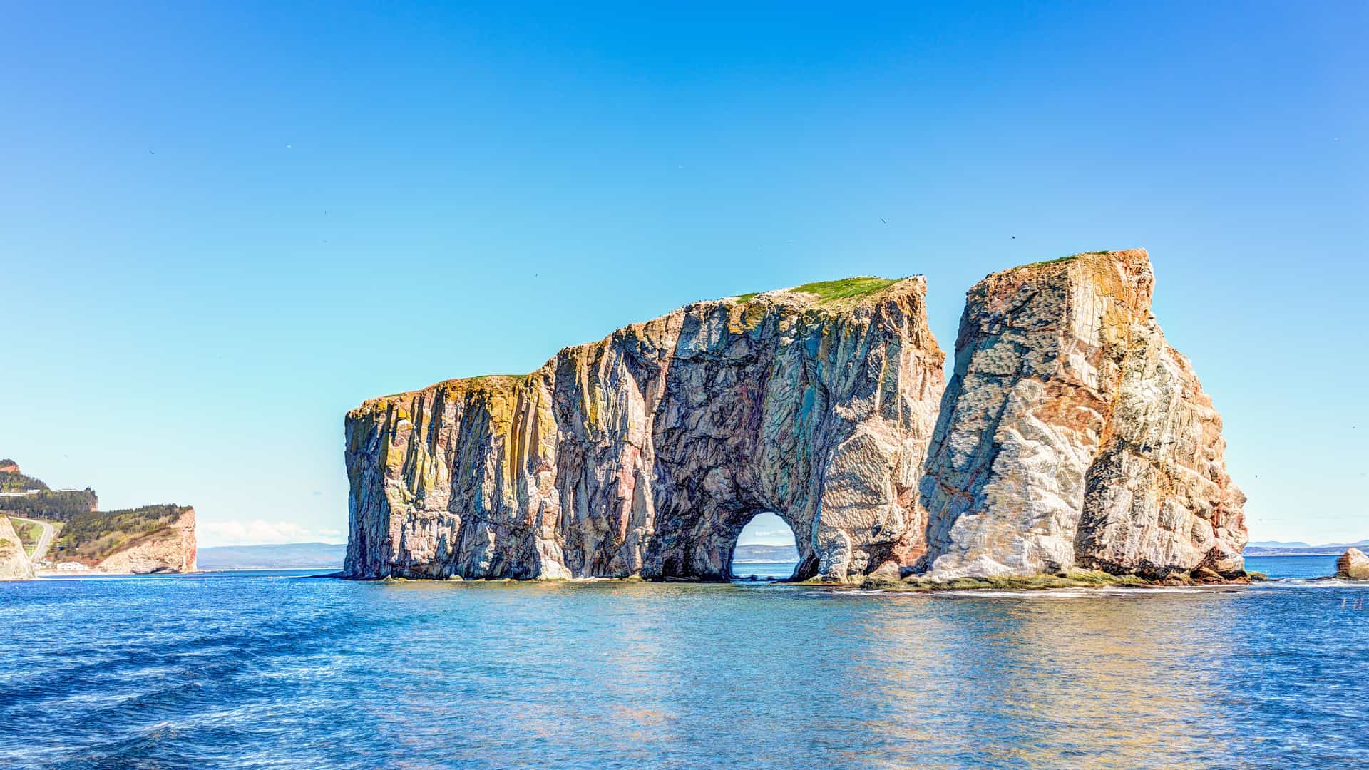 "A beautiful wide-angle shot of the iconic Percé Rock, a large limestone sea stack with a natural arch, located off the shore of Percé, Quebec, Canada.  "