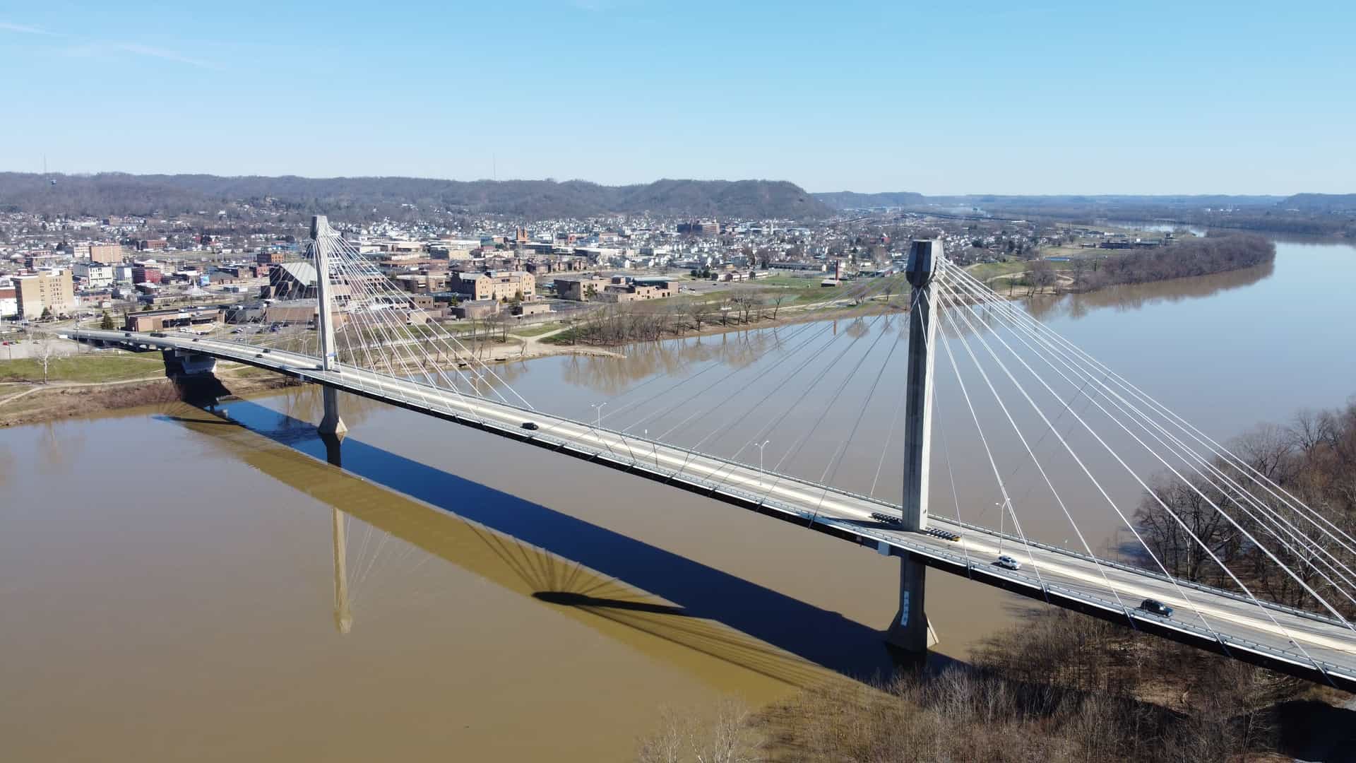 The Carl Perkins Memorial Bridge spans the brown water of the Ohio River, connecting to the skyline of Portsmouth, Ohio.