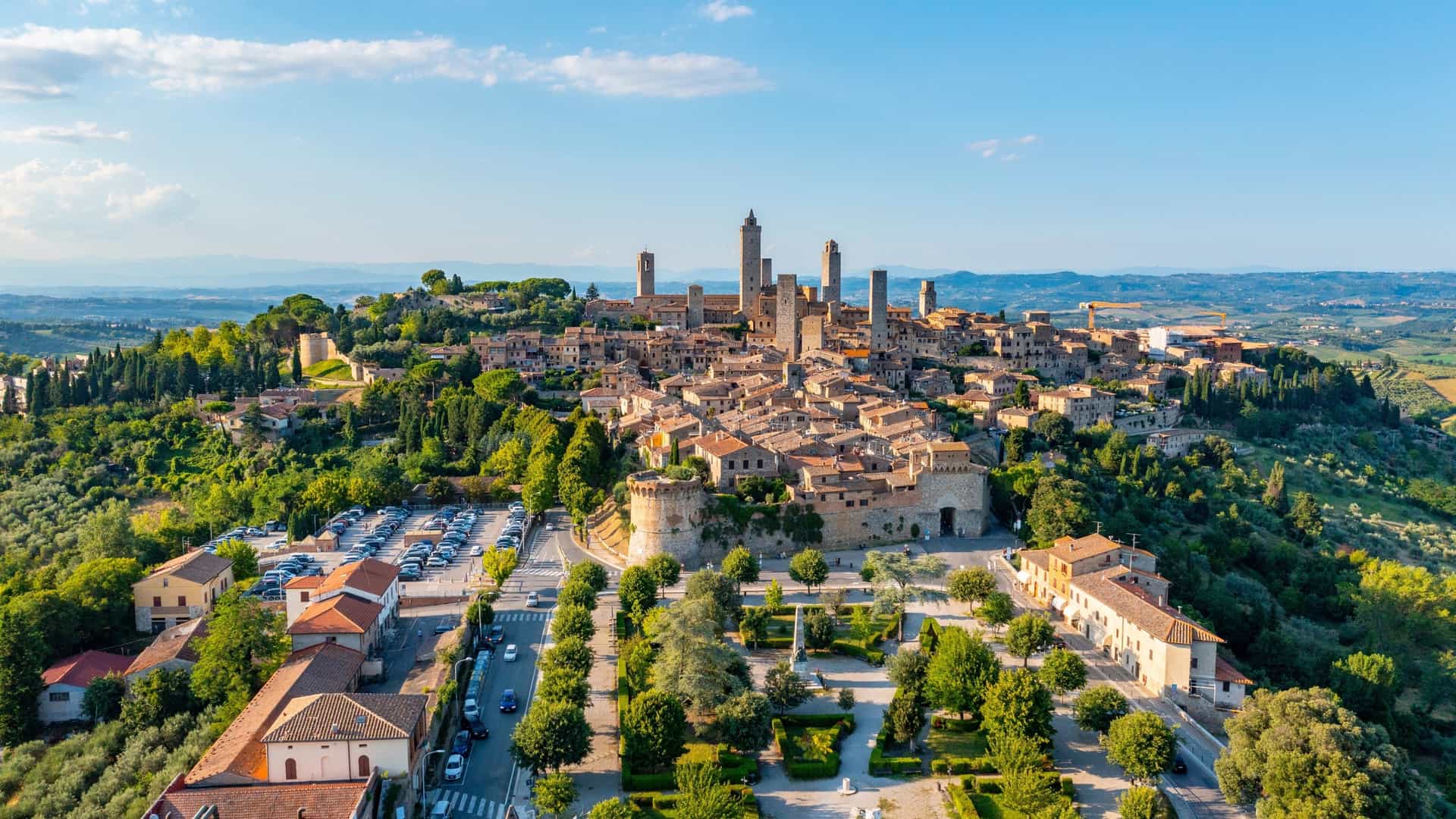 An aerial view of the walled medieval hill town of San Gimignano, famous for its cluster of intact stone towers.