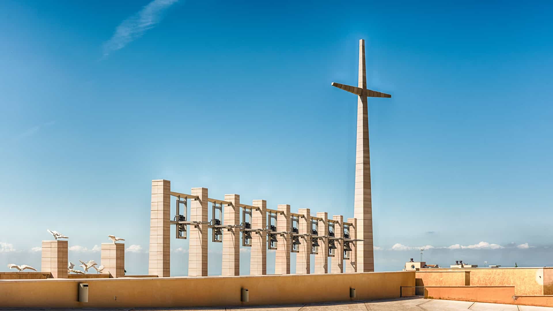 "A striking, modern church bell tower with a prominent cross, designed by Renzo Piano, at the Sanctuary of Padre Pio in San Giovanni Rotondo, Italy."