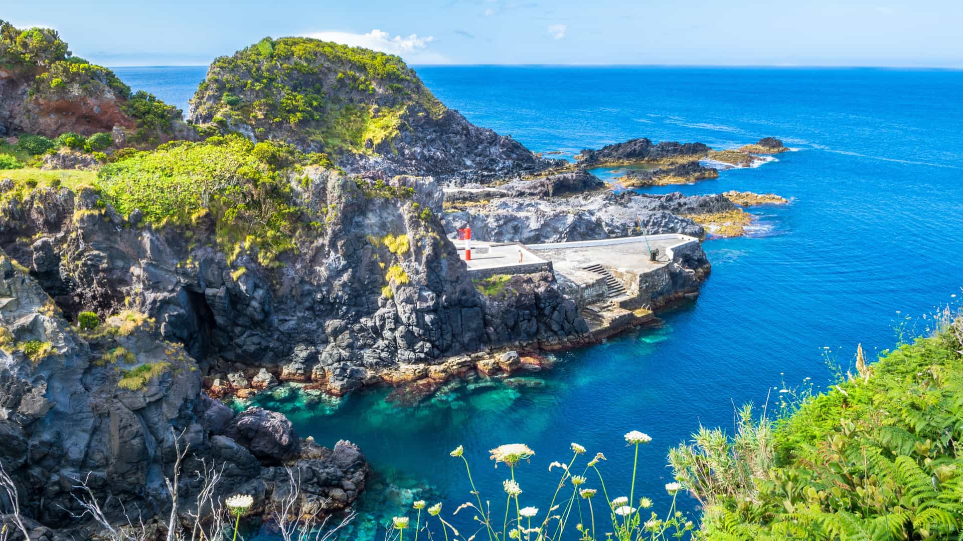 A warm sunset aerial view in Middleburg featuring a tall white water tower draped with an American flag, surrounded by tree‑lined streets, small homes, and rolling green hills glowing in golden light.