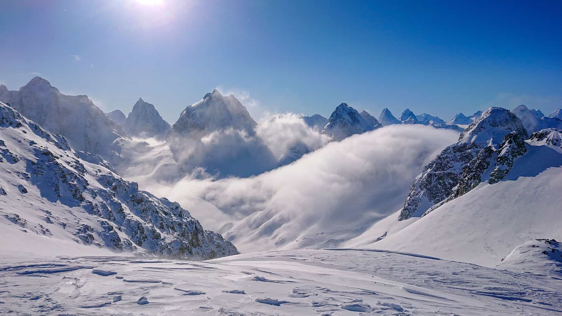"A majestic winter scene of snow-covered mountains and sharp peaks, with thick clouds blanketing the valley in the Sun Peaks area of British Columbia.  "