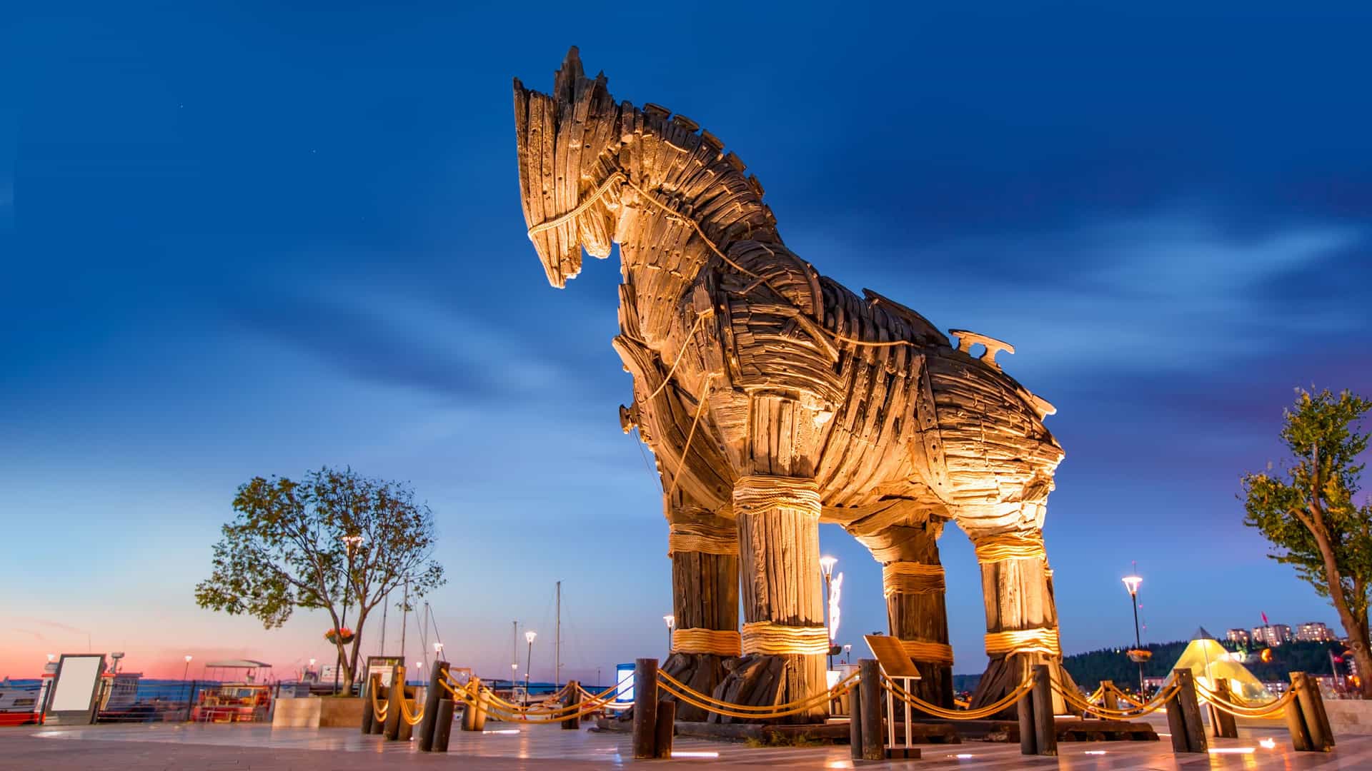 "A towering wooden Trojan Horse sculpture stands illuminated at dusk in Çanakkale, Turkey, overlooking the Aegean Sea as a modern tribute to the ancient city of Troy.  "