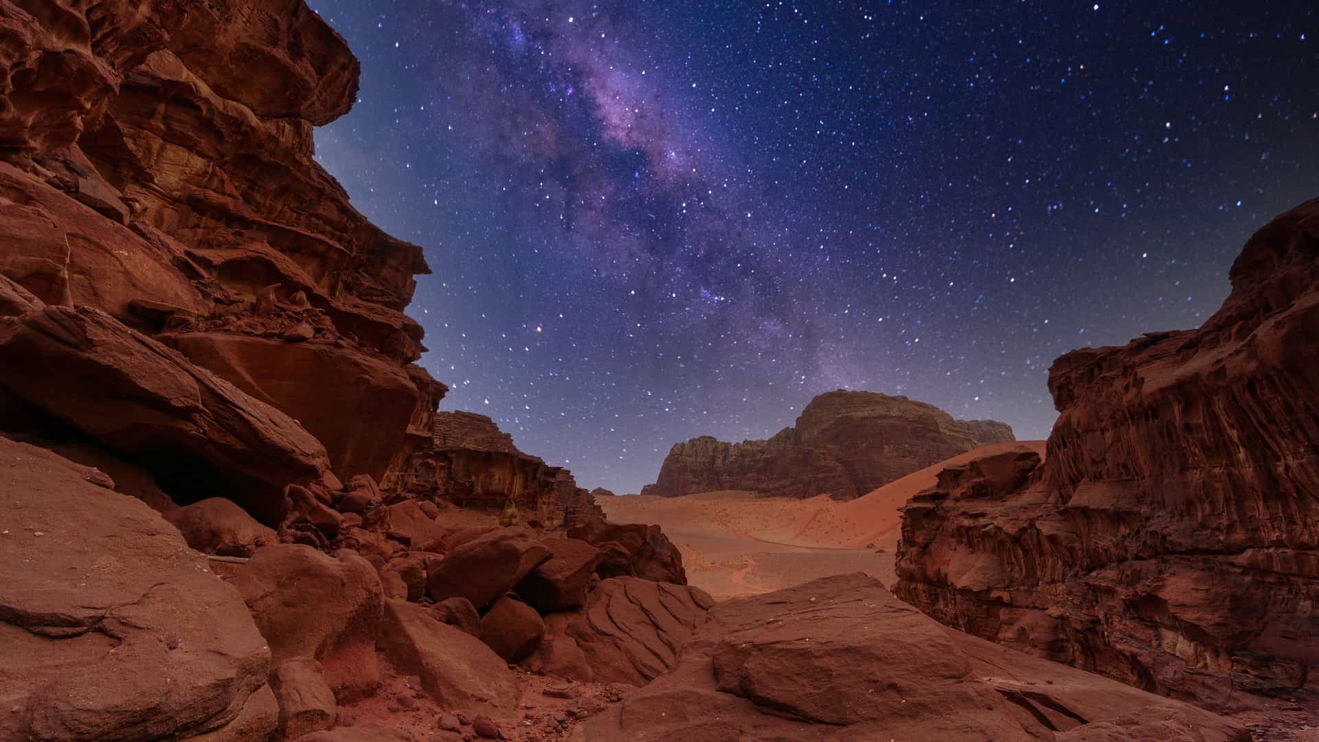 "A dramatic night sky with the Milky Way visible over the red sandstone mountains of the Wadi Rum desert in Jordan.  "