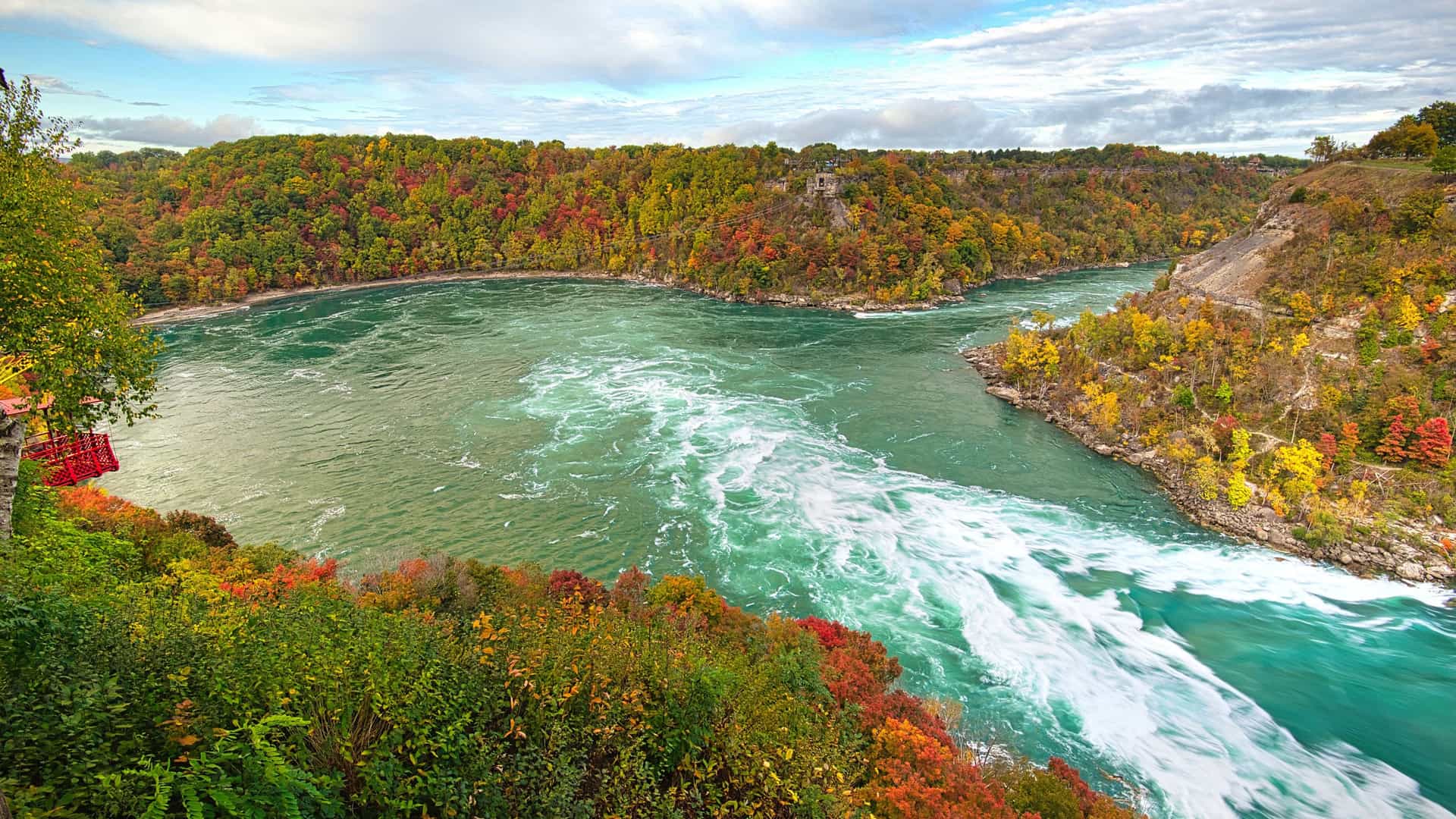 "A high-angle view of the vibrant, turquoise waters of the Niagara River flowing through the forested Niagara Gorge, a natural wonder in the Whirlpool Passage, Canada.  "