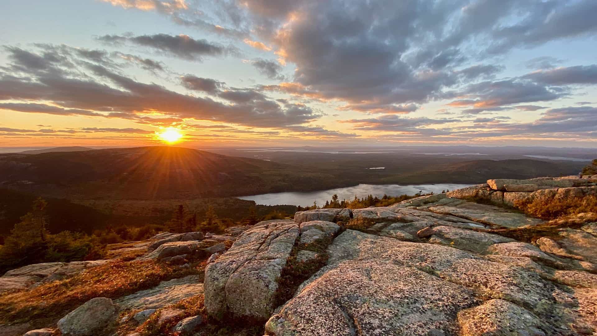 Panoramic sunrise over a vast mountain landscape and tranquil lake, representing the stunning natural beauty encountered on a Princess Cruises Canada and New England itinerary.