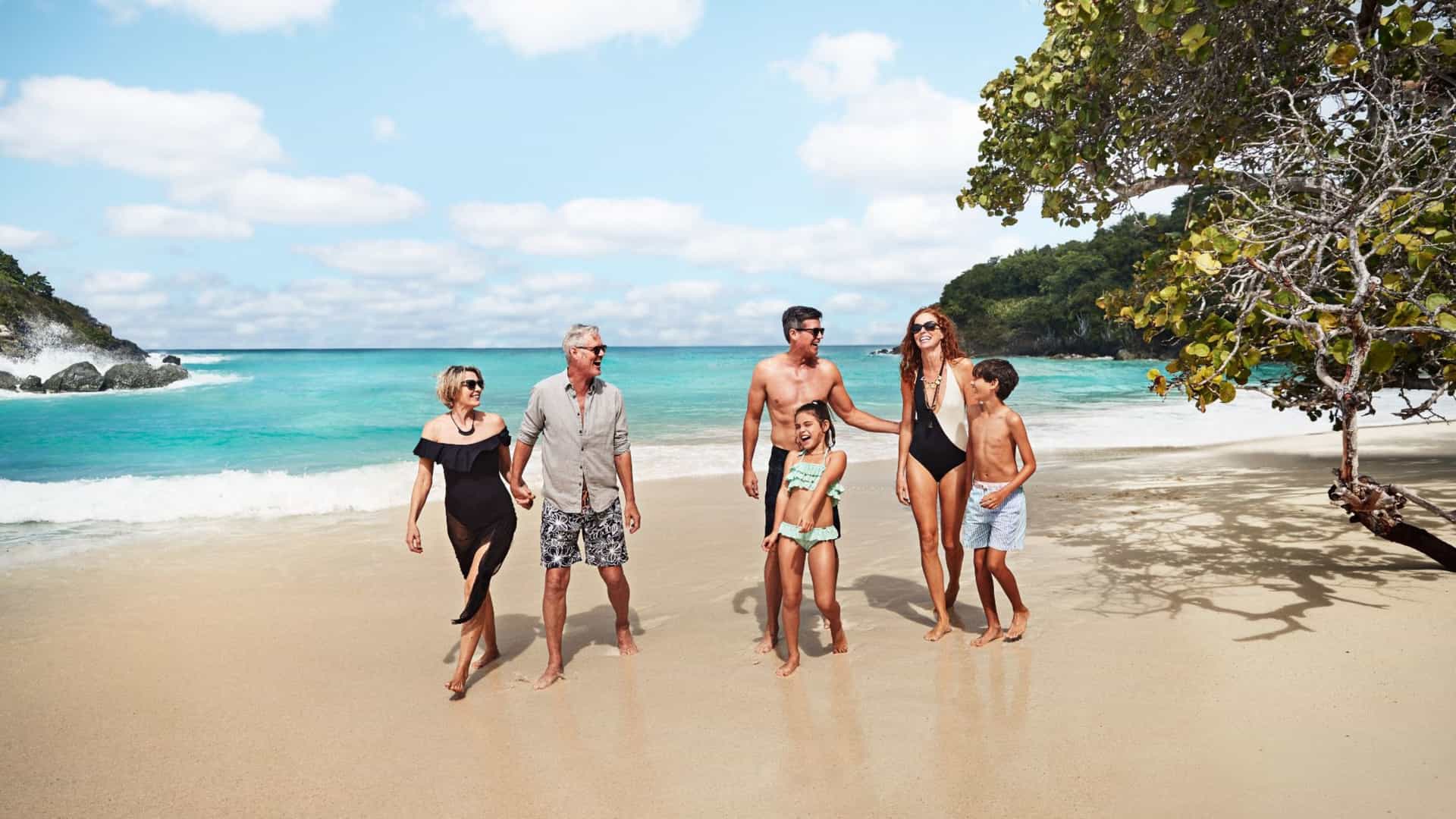 A multi-generational family enjoys a sunny day walking on a pristine white sand beach in St. John, a perfect stop on a Princess Cruises Eastern Caribbean vacation.