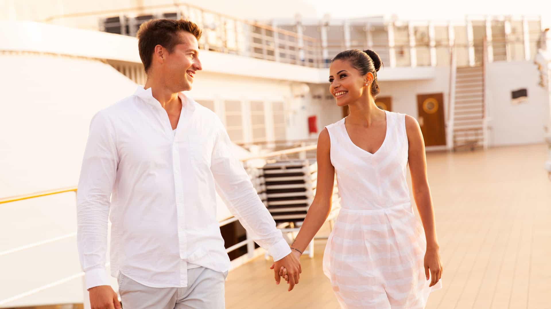 Young couple walking and holding hands on a top deck during their romantic cruise.jpg