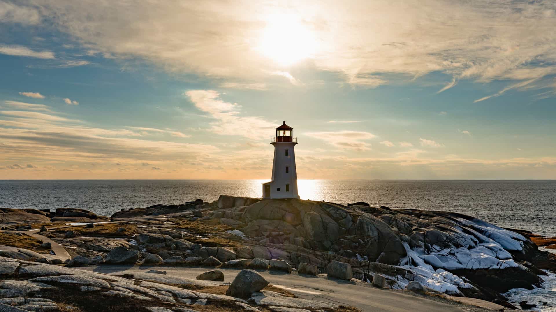 The iconic lighthouse at Peggy's Cove, Nova Scotia, stands against a beautiful sunset, a picturesque stop on a Royal Caribbean cruise to Canada and New England.