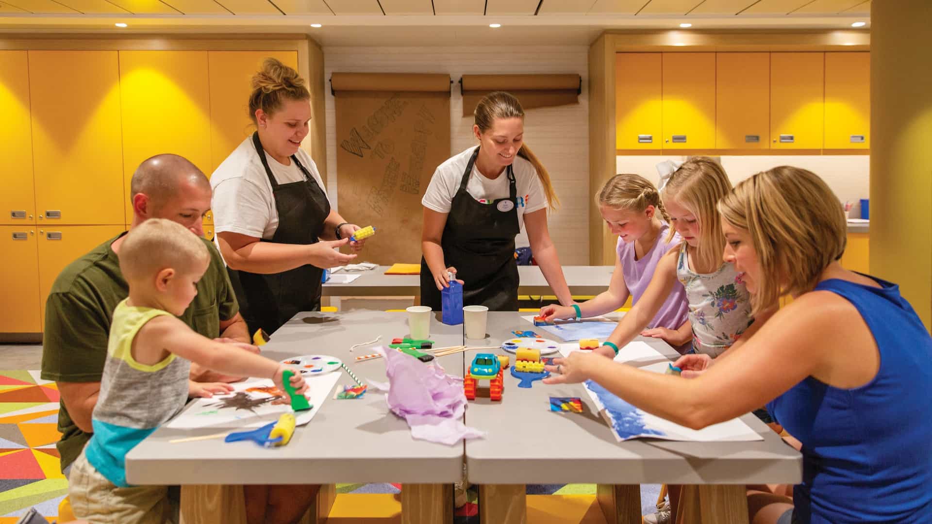 A family circled around a table engaged in a arts and craft activities under the supervision of onboard staff for the Adventure Ocean program aboard a Royal Caribbean ship.