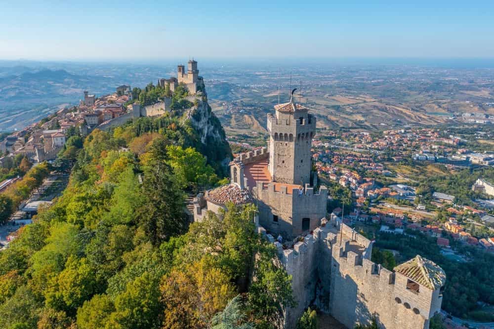 Aerial view of San Marino featuring Torre Guaita and Torre Cesta perched on Monte Titano, with medieval towers overlooking the surrounding countryside.