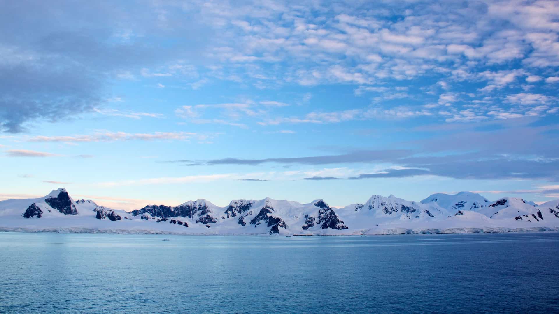 A stunning panorama of ice-covered mountains and the ocean in Antarctica, an awe-inspiring destination for an expedition cruise with Seabourn.