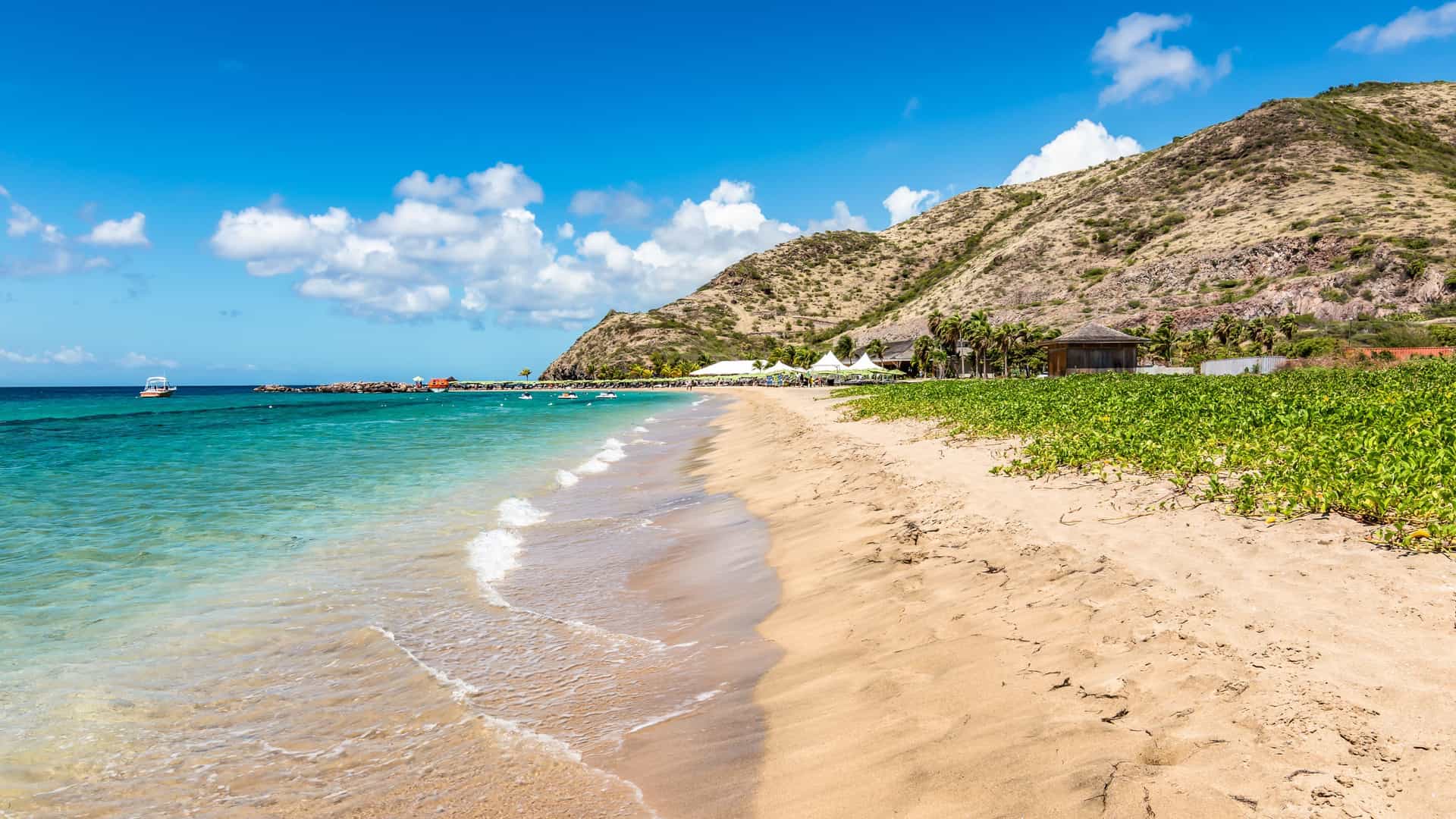 A pristine beach with turquoise water and rolling hills in St. Kitts, a beautiful destination in the Eastern Caribbean for a relaxing shore excursion on a Seabourn cruise.