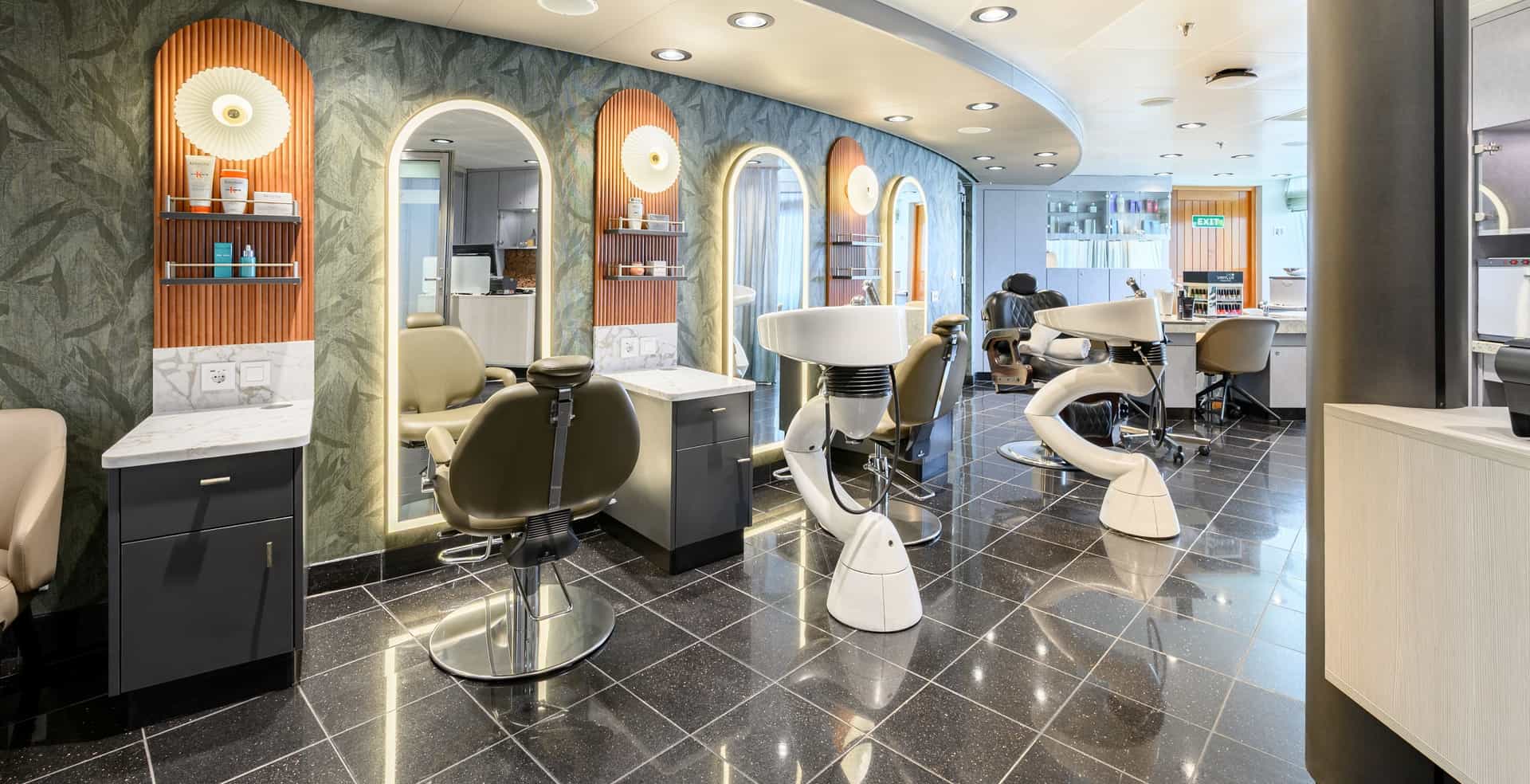 The newly transformed salon aboard the Seabourn Quest, showcasing sleek styling chairs, glowing arched mirrors with textured wood paneling, and glossy dark flooring.