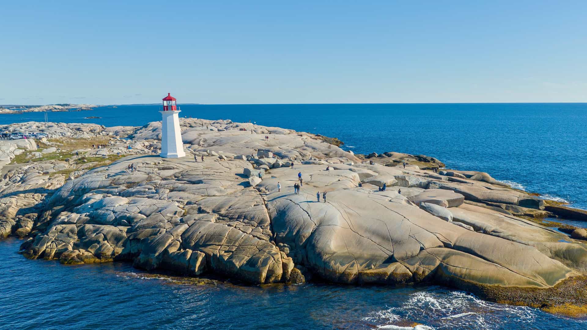 An aerial view of the iconic Peggy's Cove lighthouse on a rocky shoreline in Nova Scotia, Canada, a destination on a Silversea cruise.