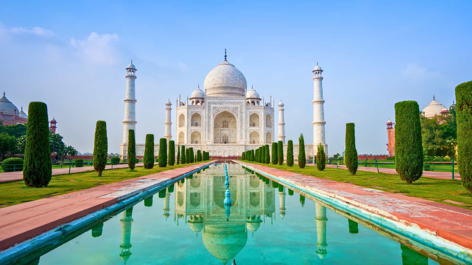The iconic Taj Mahal in Agra, India, reflected in a long pool surrounded by manicured gardens, a scenic land excursion on a Silversea cruise.