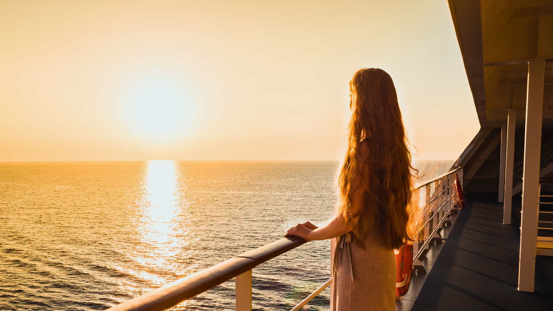 A woman enjoys the sunset over the vast ocean from the deck of a Silversea cruise ship, possibly during a Trans-Pacific voyage.