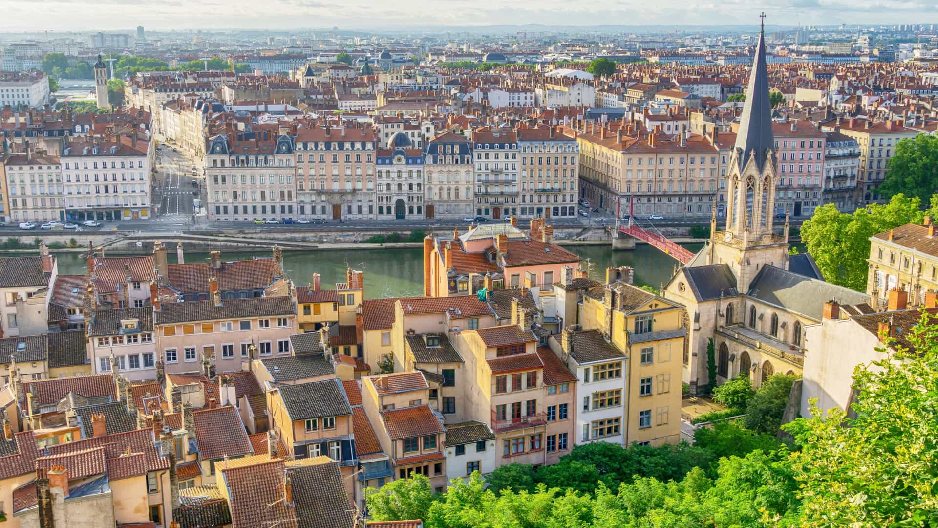 Panoramic view of a historic European city featuring traditional terracotta rooftops, a river, and a church spire on a Tauck river cruise.