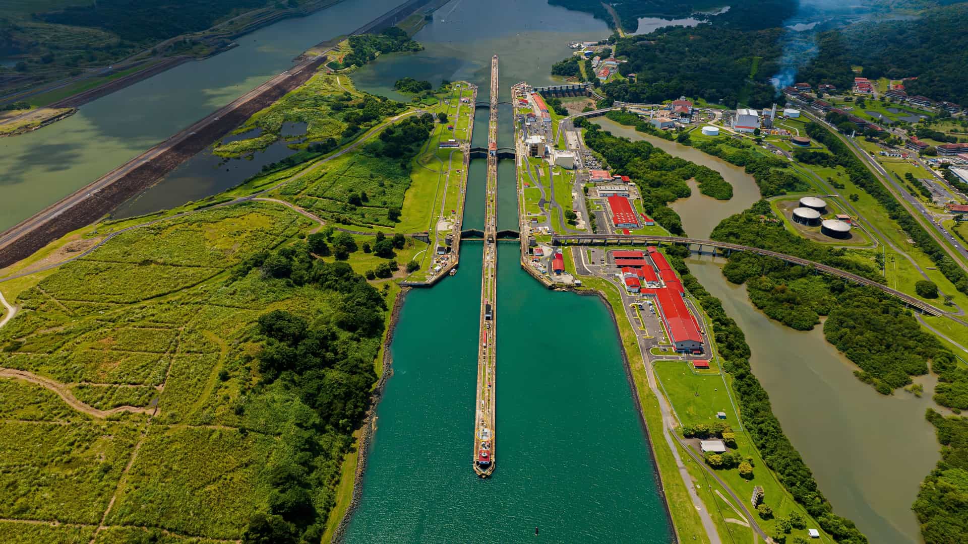 Aerial view of a ship navigating the locks of the Panama Canal surrounded by lush green landscapes on a Tauck cruise.