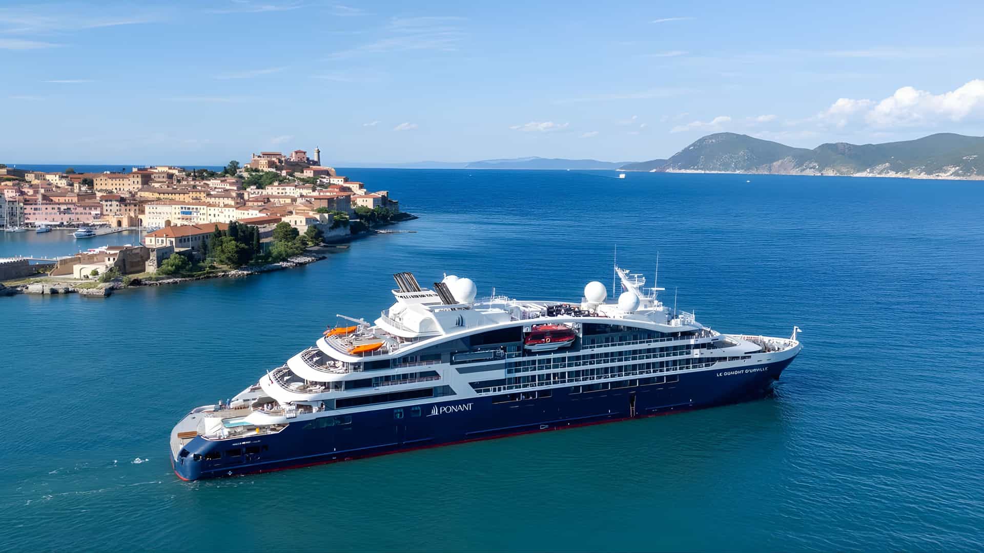 Tauck Ponant cruise ship Le Dumont D’Urville near Mediterranean coastal town